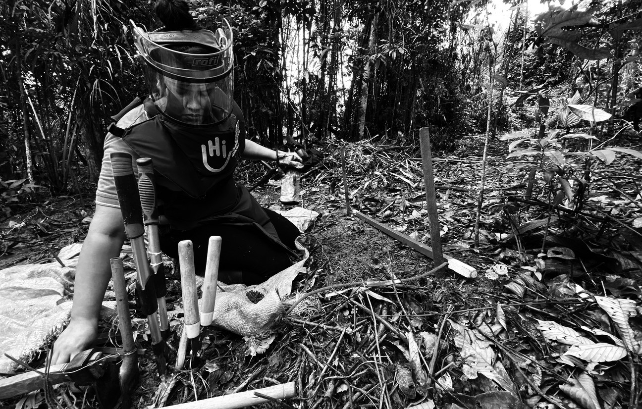 Jennifer kniet mit einigen Werkzeugen auf einem Waldboden und trägt Schutzausrüstung.