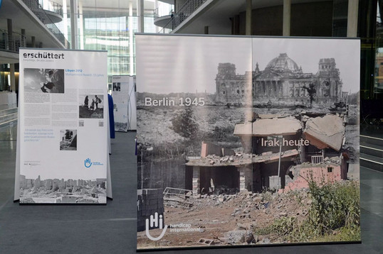 Auf dem Roll-Up liegen der Reichtsag und ein Gebäude im Irak in Trümmern.