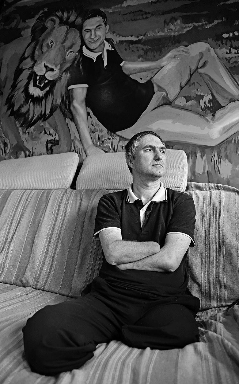 Branislav auf dem Sofa vor dem Bild seines Freundes.