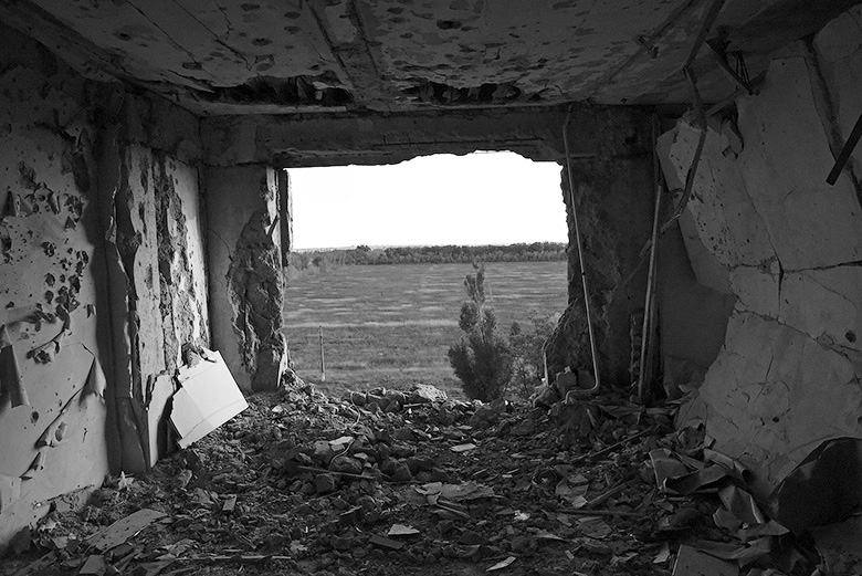 Blick aus einem zerbombten Hausa auf ein weites Feld.