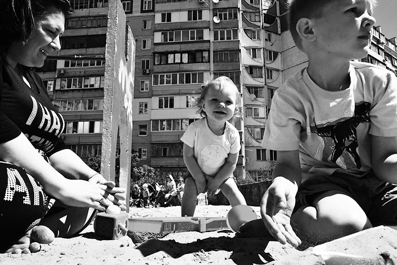 Kinder spielen im Sandkasten vor einem Wohnblock.
